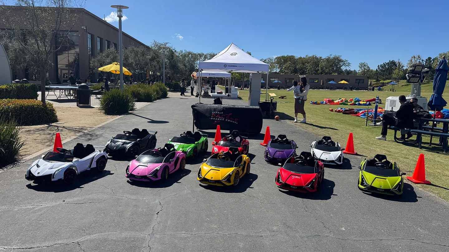 The full Little Racers OC fleet of branded ride-on Lamborghinis lined up beside a Little Racers Orange County table at a Southern California community event